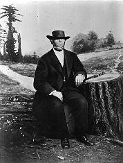 A black-and-white portrait of McKiernan seated on a log