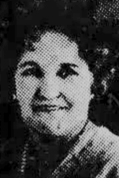 A smiling middle-aged white woman with dark curly hair