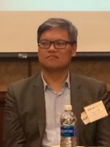 Headshot of Shih, who is in front of a computer projection and behind a water bottle