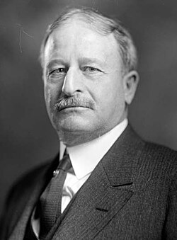 Monochromatic photograph of a man with a mustache in a suit