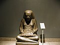 Seated scribe with part of scribe equipment on shoulders(2-basin mixing palette over left shoulder)