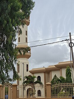 A mosque with beige walls and four spires topped with green domes
