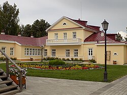 A peach-colored prune-tiled three-story house with single-story aisles surrounded by trees