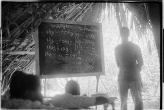 Teacher explaining the decimal system of weights using a blackboard, Guinea-Bissau, 1974
