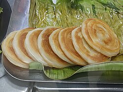 A stack of small, round parottas with spiraling layers.