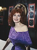 Woman with dark red hair smiling and facing at 45 degrees toward the air
