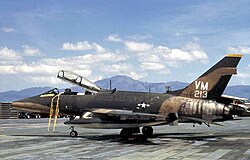 An F-100 Super Sabre jet aircraft on a runway at a military airfield
