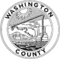 A round seal with a black-and-white depiction of a factory and the county outline