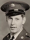 Man with army uniform looking at camera with tilted hat.