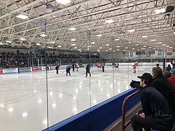 Interior view of arena showing the ice surface, seating area and a youth hockey game