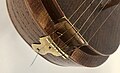 The strings are tied off in a loop and anchored on the metal plate at the bottom.  the top string is set slightly apart from the 4 drone strings, and is elevated higher above the finger board as well.