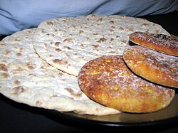 On the left, two large flatbreads that are bumpy and light-colored with dark spots. On the right, a smaller, thicker flatbread that has a darker color.