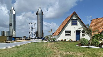 Two silver Starship prototypes standing behind a small tiki bar.