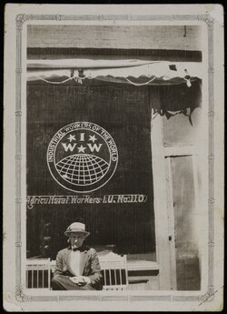 A man sits in front of the windows of the IWW offices in Yakima, Washington.