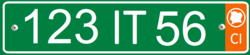 Plate with white alphanumeric characters on a green background, and an orange bar on the right side containing the white letters CI at the bottom, and a white silhouette of the Ivory Coast inside a white circle at the top.