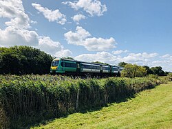 Shot of a field with a train running along a straight track in the distance