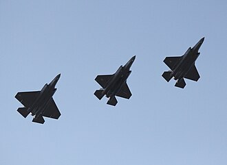 F-35 variants flying in formation. The F-35C (left) has a larger wing than other variants, while the F-35B (center) has a shorter nozzle and no tailhook.