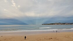 Atmospheric effect of anticrepuscular rays opposite the sunset in the bay of San Lorenzo, Gijón, Spain