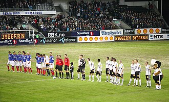 A line of footballers, in blue and white, respectively, at a large stadium