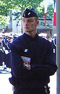 A CRS police officer in normal gear, including a bonnet de police.
