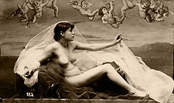 Black and white photograph of a nude female figure in classical pose