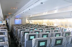 Interior view. Seats are separated by two aisles, in 3–4–3 configuration. A TV is positioned towards the front of aircraft.