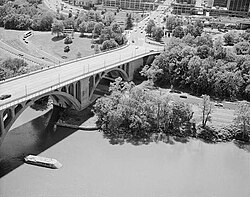 Aerial view of Key Bridge and George Washington Memorial Parkway, with pier of Aqueduct Bridge visible in the foreground and remnant of Aqueduct Bridge abutment visible on the Virginia shoreline (c. 1990)