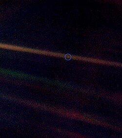 A tiny, pale blue dot is contrasted against the vastness of space