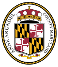 An oval seal featuring a shield with heraldic symbols