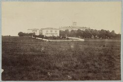 black and white photo of field with several buildings in the distance