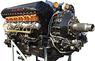 A front right view of a black-painted aircraft piston engine. The words 'Rolls-Royce' appear in red text on the camshaft cover.
