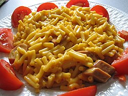 A Canadian meal—Kraft Dinner with added Cheddar that has been integrated with sliced vegetarian hot dog and fresh tomato slices