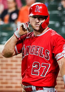 A man in a red baseball jersey and batting helmet with gray pants