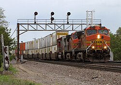 An outbound (westbound from Chicago) BNSF Railway intermodal train crosses over to the middle track just west of the Naperville Metra station in 2010.