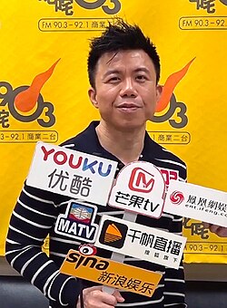 a man wearing a striped t-shirt and being interviewed by the media