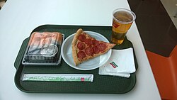 A tray with a pepperoni pizza slice, a plastic cup of beer, and another item.