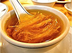 alt= a bowl of light-brown-coloured soup with numerous strands of orange-coloured flesh