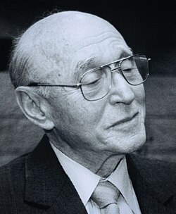 Photograph of an elderly man with grey hair, on a black background