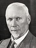 Close-up black-and-white portrait of Jan Smuts wearing a suit against a neutral background with a neutral expression.