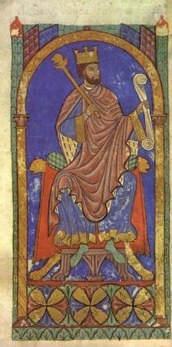 A bearded man wearing a crown sitting on a throne
