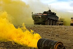 Smoke billowing from a yellow M18 with Polish forces in the background, Afghanistan, February 23, 2010.