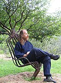 Artist Peter Cook seated in a living garden chair (see Tree shaping)