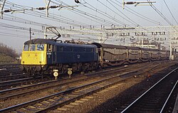 A Class 85, which is blue with a yellow front and cubic, hauling coaches. The photo is taken with three unoccupied tracks in between, and electric wires above