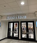 Two sets of double doors with large glass windows, slightly recessed into the wall, below an overhang with lettering that reads "University of Minnesota Bookstore". On either side of the doors, on the wall before it recesses, is a television.