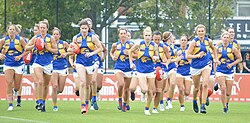 A group of female Australian rules footballers jogging together