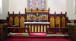 Panoramic photograph of the hand carved and painted cedar woodwork in the St John's chancel, with red carpet