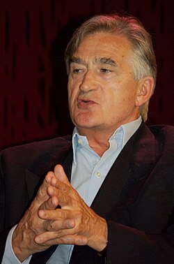 Colour photograph of Antony Beevor in dark jacket, without tie, speaking at a meeting