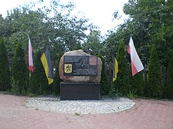 A commemorative stone surrounded by the flag of Kashubia and Poland