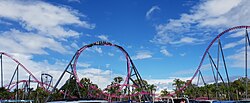 A train twisting through DC Rivals HyperCoaster's non-inverting loop, seen from the car park