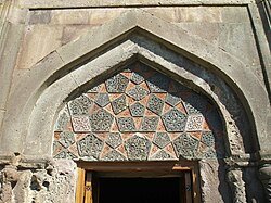 Intricately detailed tympanum above the portal of the zhamatun, an adaptation of Seljukid ablaq stonework